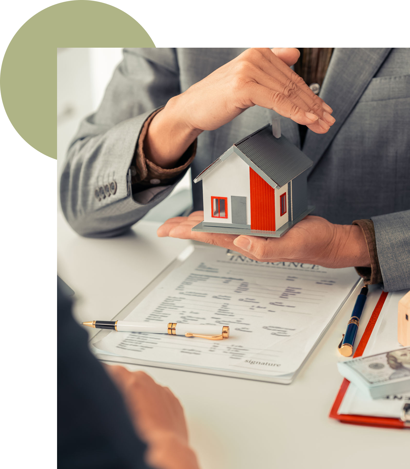 Hands holding model house over documents.