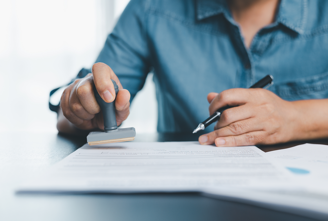 Person stamping a document, holding pen.