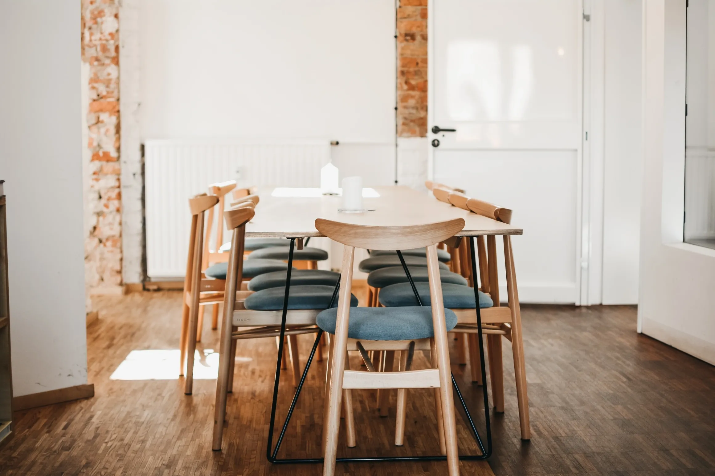 Bright dining area with wooden table and chairs, minimalistic design.